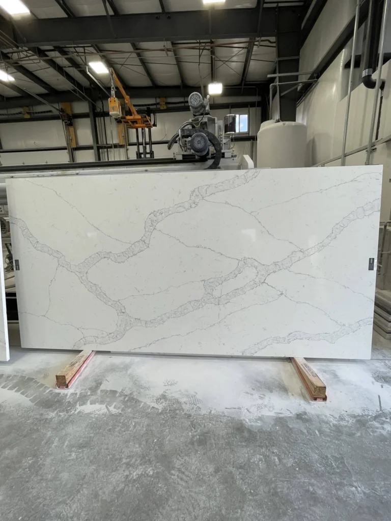Large white marble slab with gray veining in an industrial workshop setting.